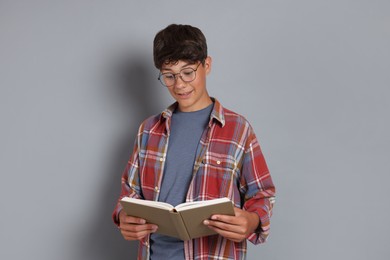 Photo of Teenage boy reading book on grey background