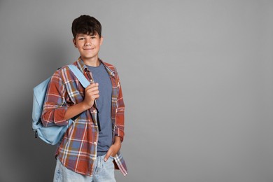 Photo of Teenage boy with backpack on grey background, space for text