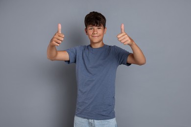 Photo of Teenage boy showing thumbs up on grey background