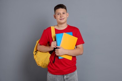 Photo of Teenage boy with notebooks and backpack on grey background