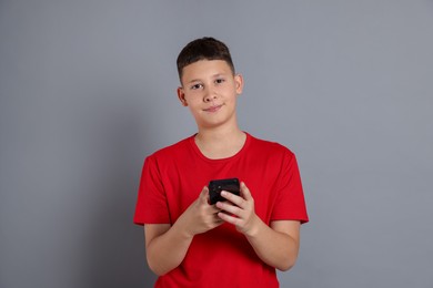 Photo of Teenage boy with smartphone on grey background