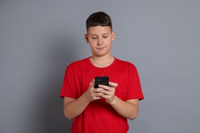 Photo of Teenage boy with smartphone on grey background