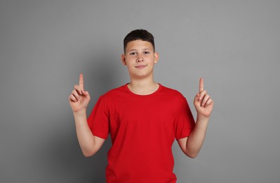 Photo of Teenage boy pointing at something on grey background