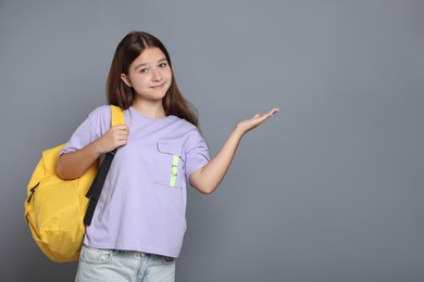 Photo of Teenage girl with backpack on grey background, space for text