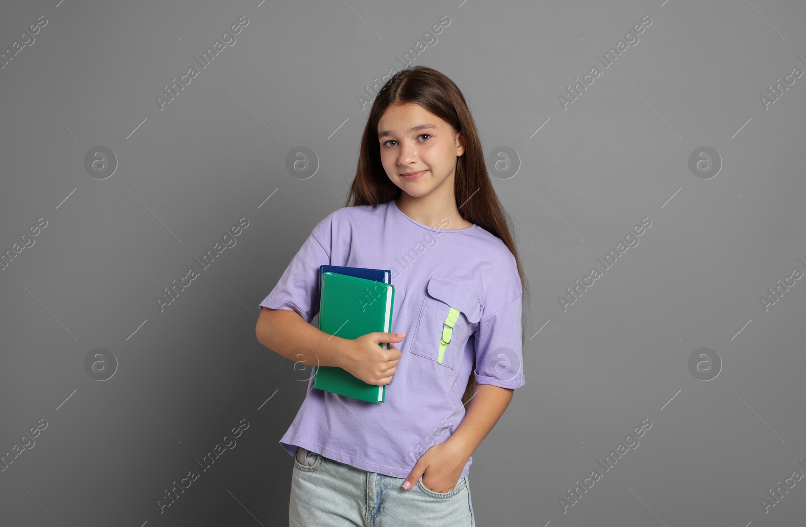Teenage girl with books on grey background Photo of Teenage girl with books on grey background