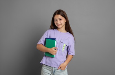 Photo of Teenage girl with books on grey background