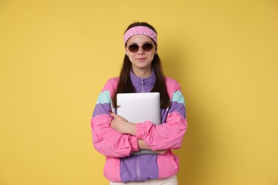 Photo of Teenage girl in sunglasses with laptop on yellow background