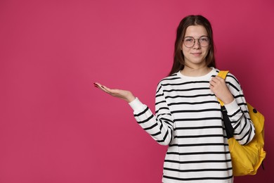 Photo of Teenage girl in glasses with backpack on crimson background, space for text