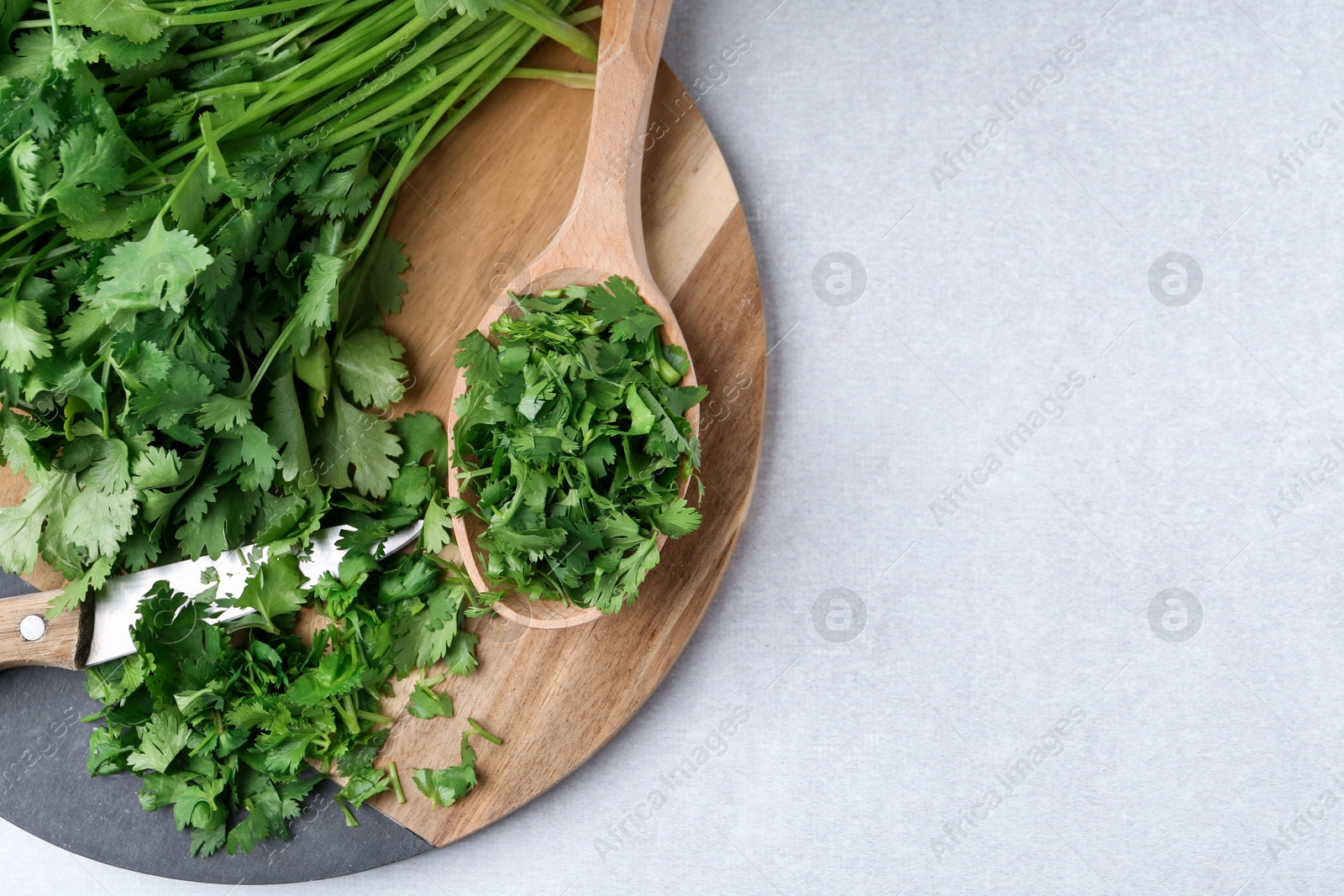 Photo of Fresh green cilantro and knife on light table, top view. Space for text