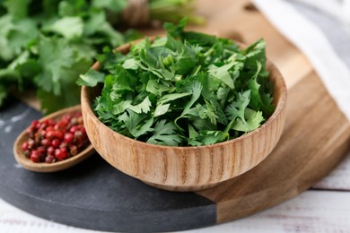 Photo of Fresh green cilantro and peppercorns on white wooden table, closeup