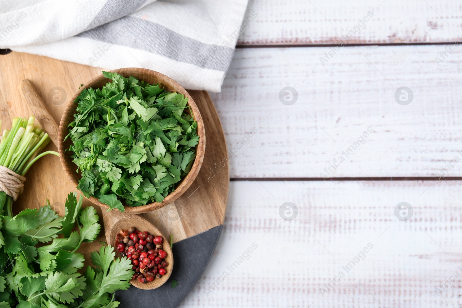 Photo of Fresh green cilantro and peppercorns on white wooden table, top view. Space for text