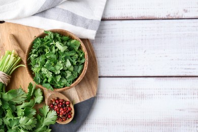 Photo of Fresh green cilantro and peppercorns on white wooden table, top view. Space for text