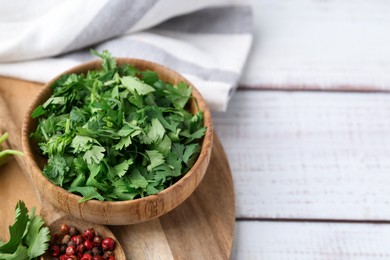 Photo of Fresh green cilantro and peppercorns on white wooden table, closeup. Space for text