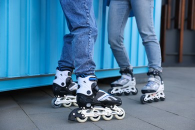 Photo of Couple with roller skates near light blue wall outdoors, closeup