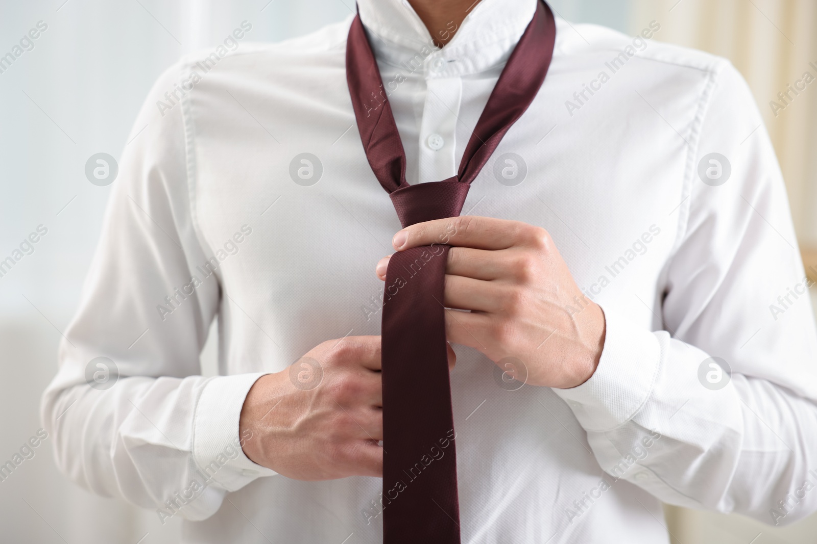 Man tying stylish necktie at home, closeup Photo of Man tying stylish necktie at home, closeup