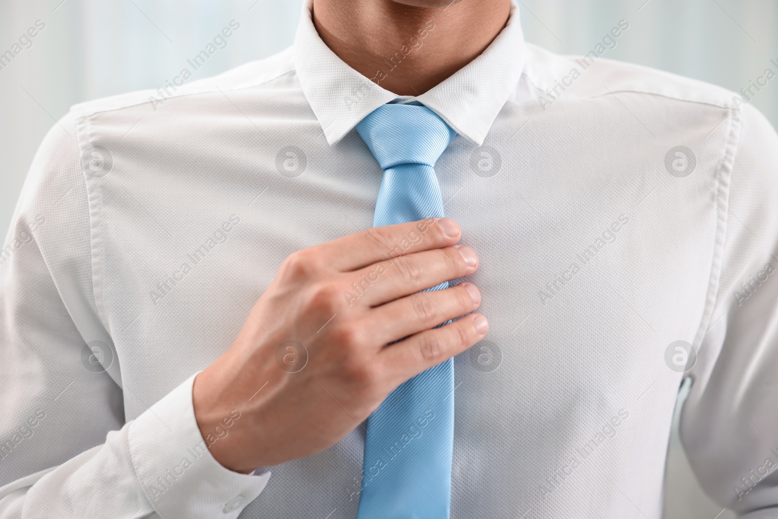 Man tying stylish necktie at home, closeup Photo of Man tying stylish necktie at home, closeup