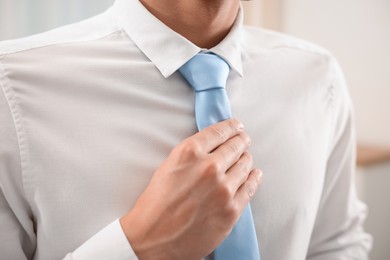 Photo of Man tying stylish necktie at home, closeup