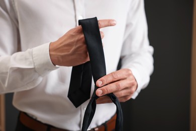 Photo of Man with stylish black necktie at home, closeup