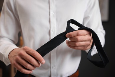 Photo of Man with stylish black necktie at home, closeup