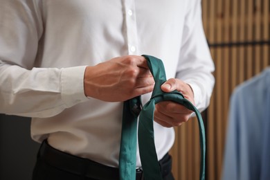Photo of Man with stylish green necktie at home, closeup