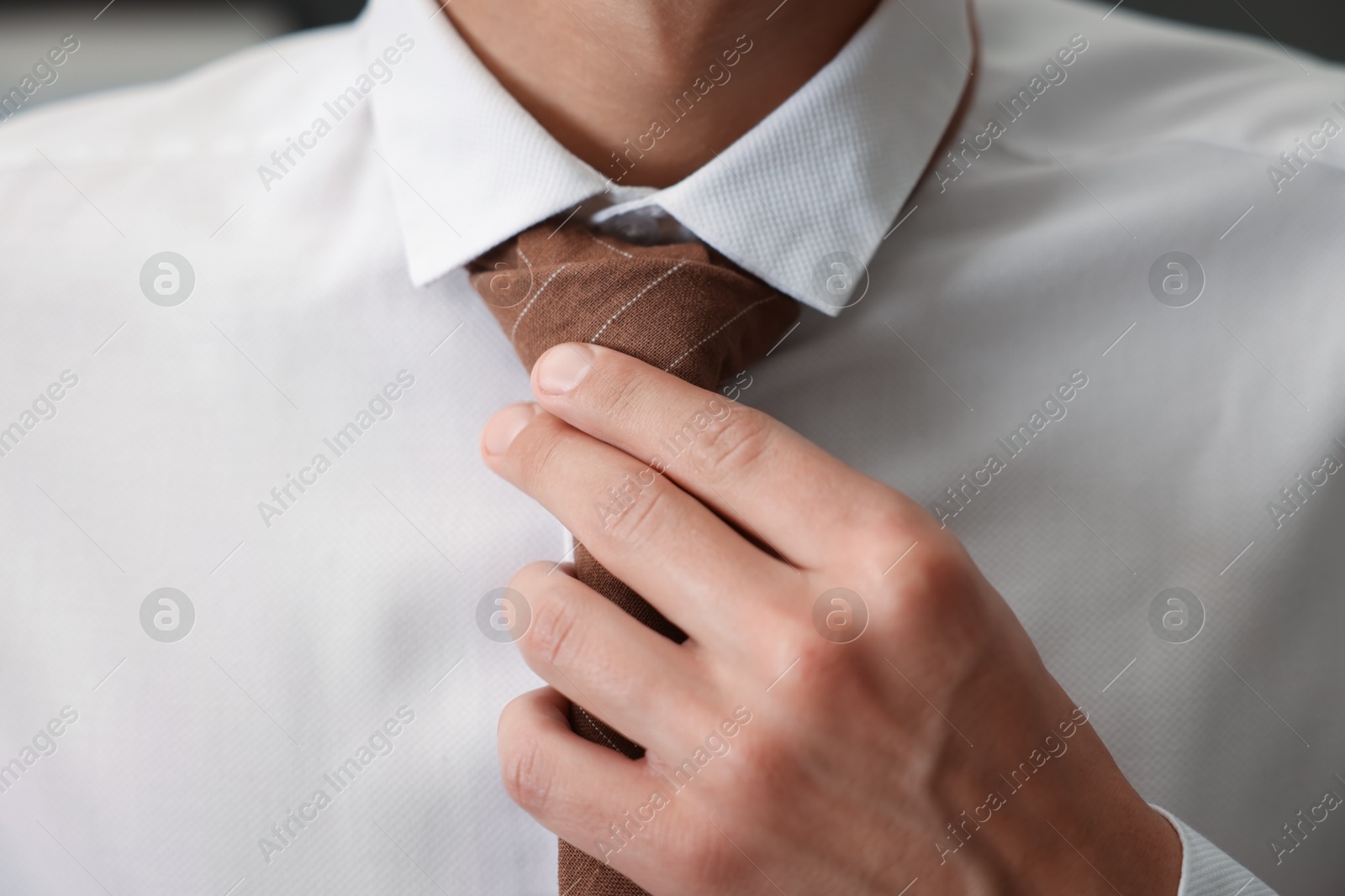 Man tying stylish necktie at home, closeup Photo of Man tying stylish necktie at home, closeup