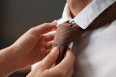 Photo of Woman tying man's necktie at home, closeup