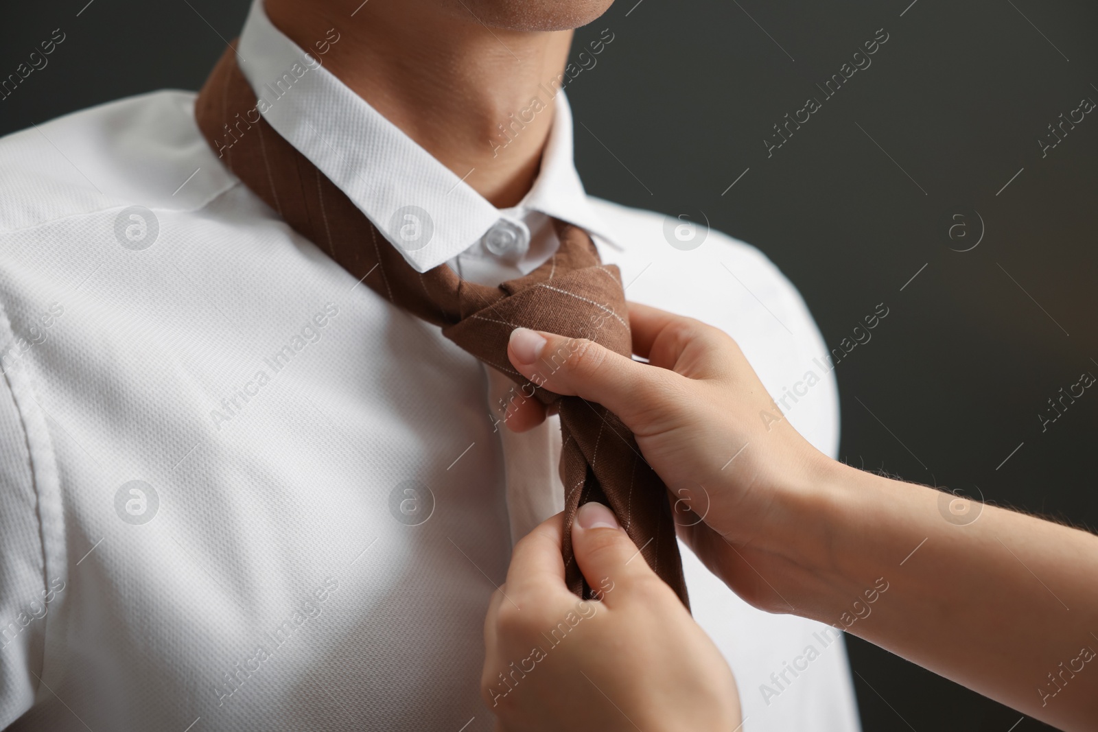 Woman tying man's necktie at home, closeup Photo of Woman tying man's necktie at home, closeup