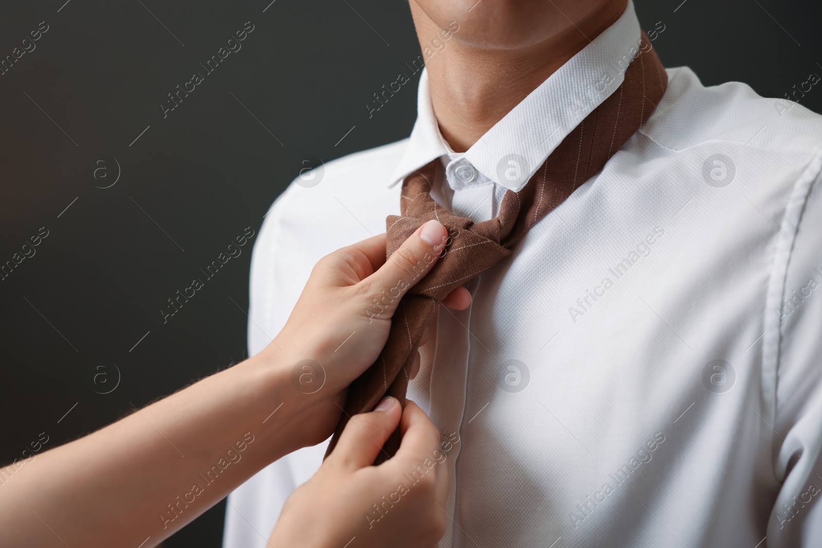 Woman tying man's necktie at home, closeup Photo of Woman tying man's necktie at home, closeup