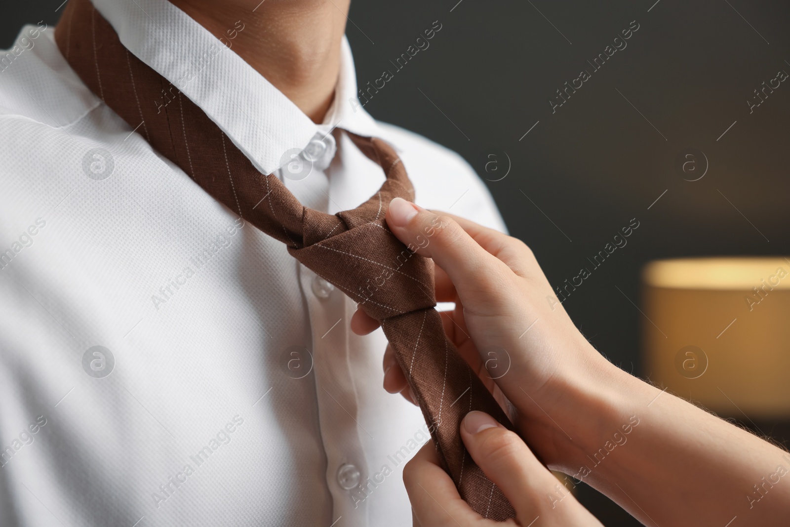 Woman tying man's necktie at home, closeup Photo of Woman tying man's necktie at home, closeup