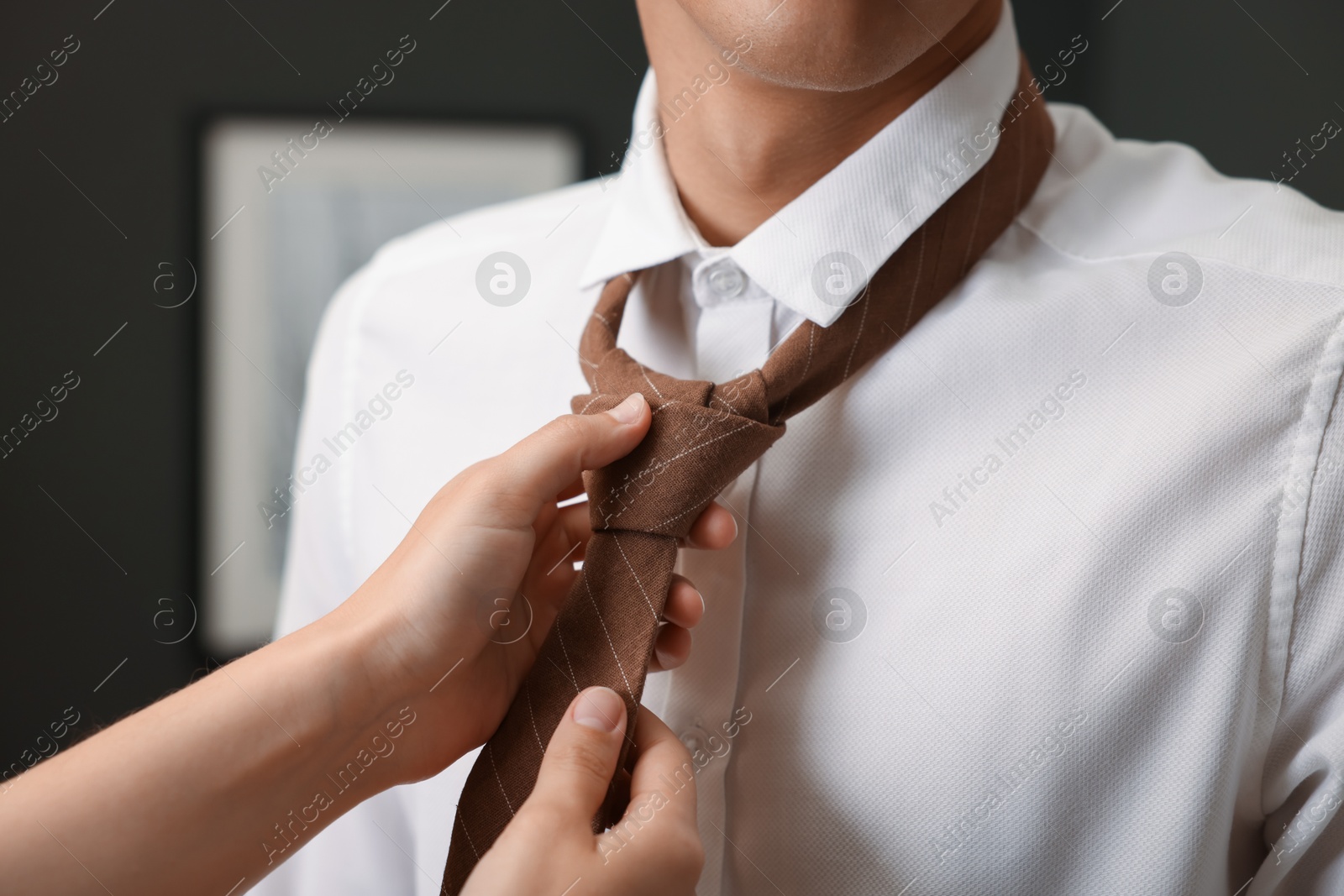 Woman tying man's necktie at home, closeup Photo of Woman tying man's necktie at home, closeup
