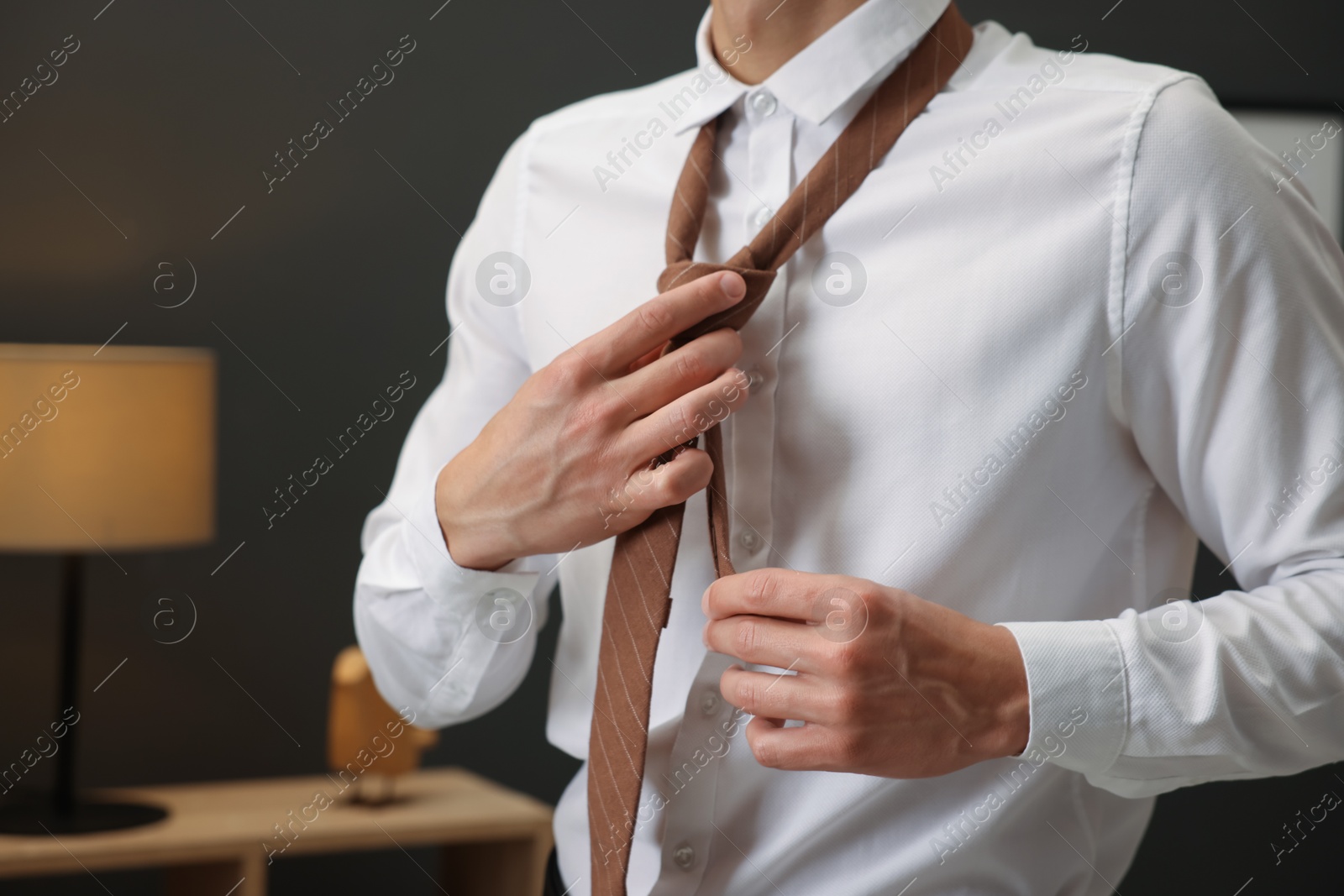Man tying stylish necktie at home, closeup Photo of Man tying stylish necktie at home, closeup