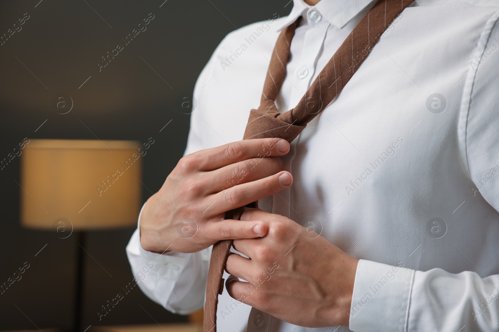 Photo of Man tying stylish necktie at home, closeup