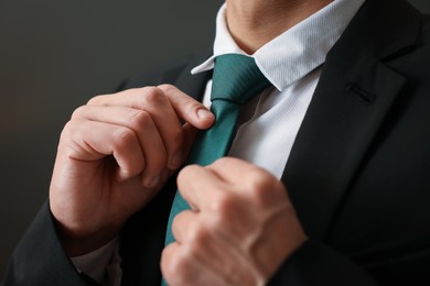 Photo of Man tying stylish necktie at home, closeup