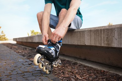 Photo of Man putting on roller skates outdoors, closeup