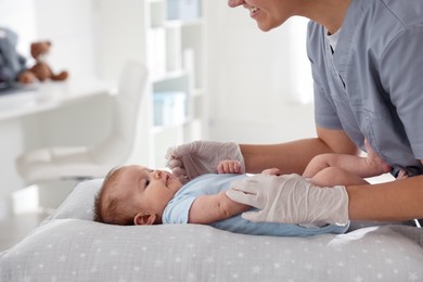Photo of Pediatrician examining baby at table in clinic, closeup