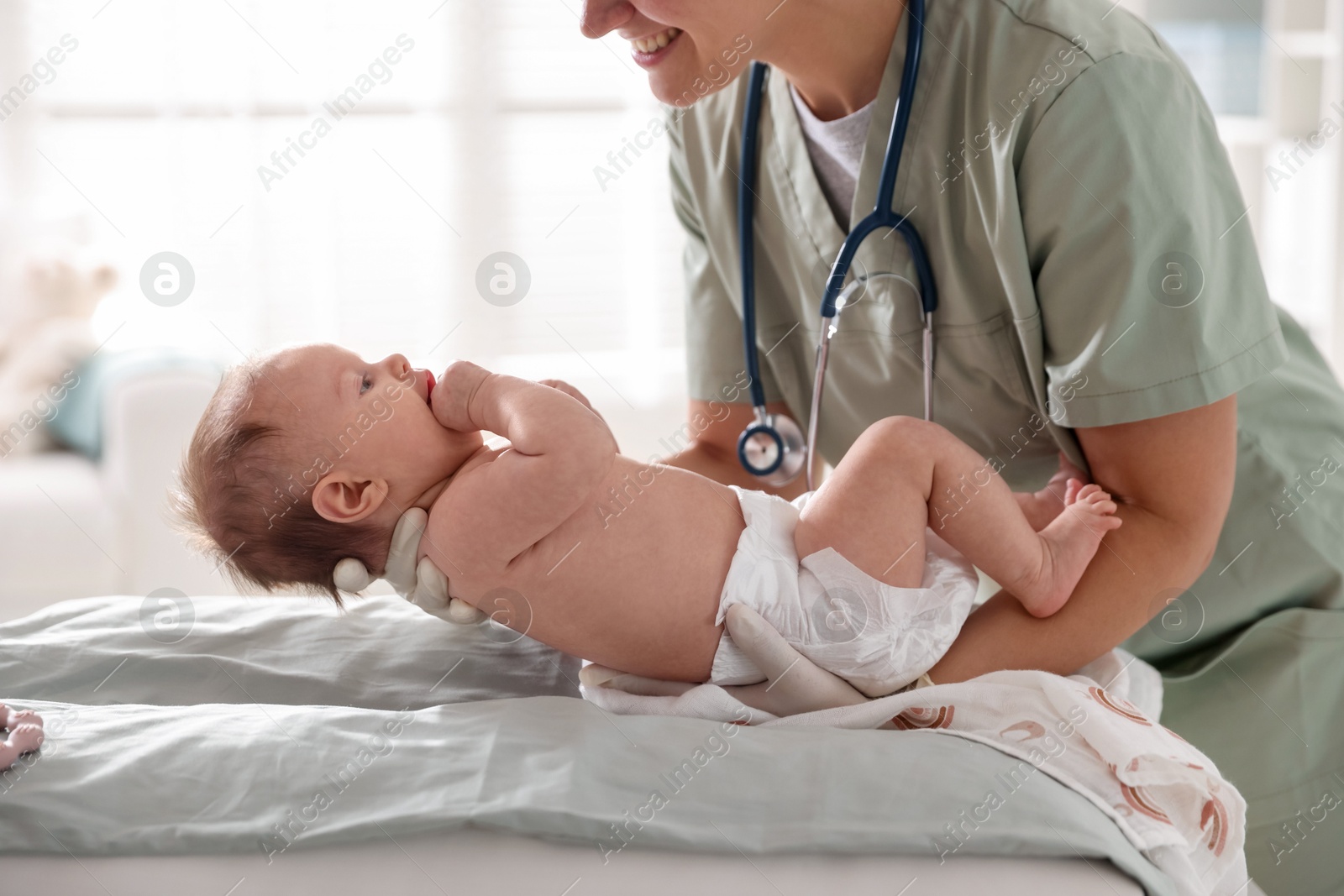 Pediatrician examining baby at table in clinic, closeup Photo of Pediatrician examining baby at table in clinic, closeup