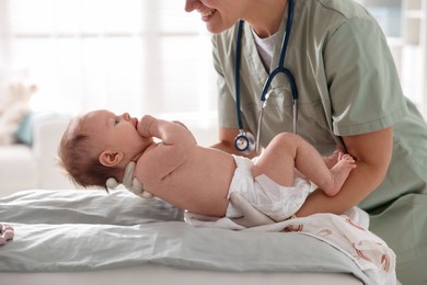 Photo of Pediatrician examining baby at table in clinic, closeup