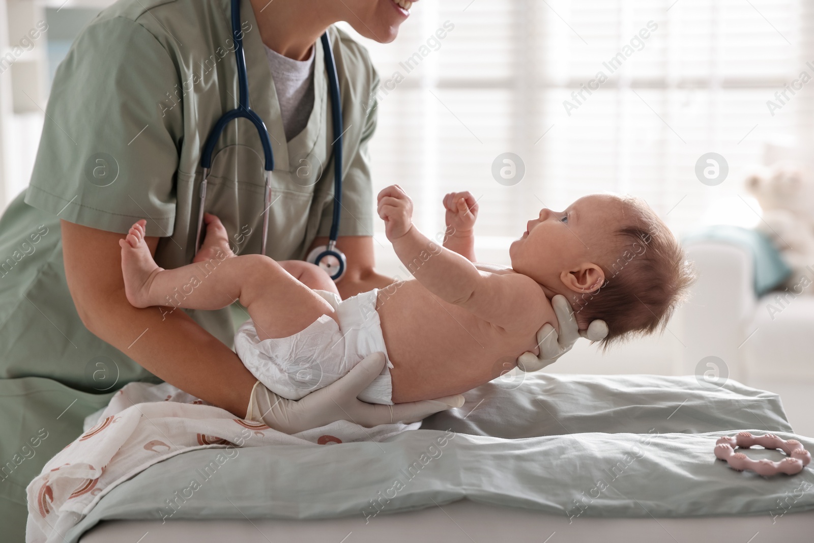 Photo of Pediatrician examining baby at table in clinic, closeup