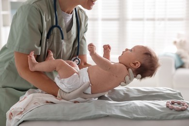 Photo of Pediatrician examining baby at table in clinic, closeup