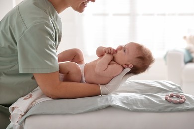 Photo of Pediatrician examining baby at table in clinic, closeup