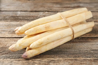 Photo of Raw white asparagus spears on wooden table, closeup