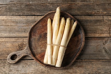 Photo of Bunch of raw white asparagus spears on wooden table, top view