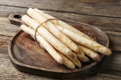 Photo of Raw white asparagus spears on wooden table, closeup