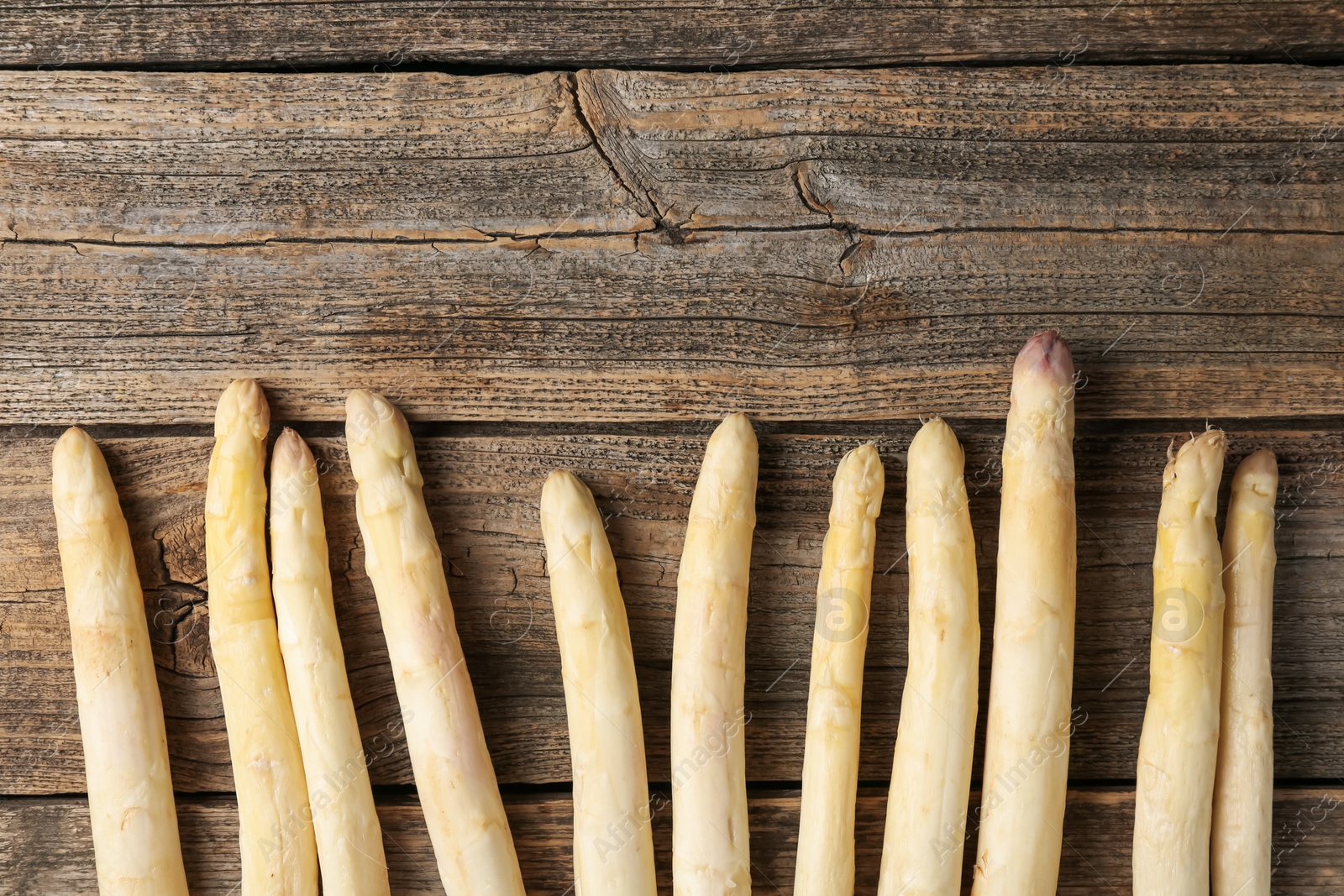 Raw white asparagus spears on wooden table, flat lay. Space for text Photo of Raw white asparagus spears on wooden table, flat lay. Space for text