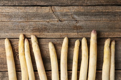 Photo of Raw white asparagus spears on wooden table, flat lay. Space for text