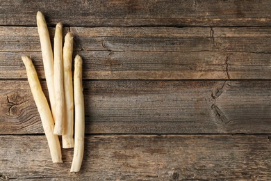 Photo of Raw white asparagus spears on wooden table, flat lay. Space for text