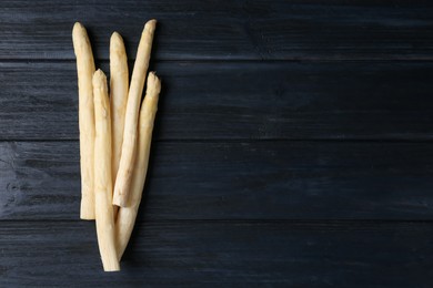 Photo of Raw white asparagus spears on black wooden table, flat lay. Space for text