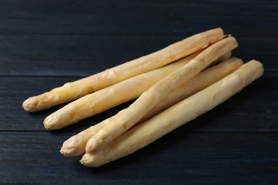 Photo of Raw white asparagus spears on black wooden table, closeup