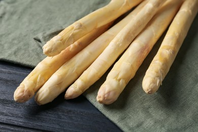 Photo of Raw white asparagus spears on black wooden table, closeup