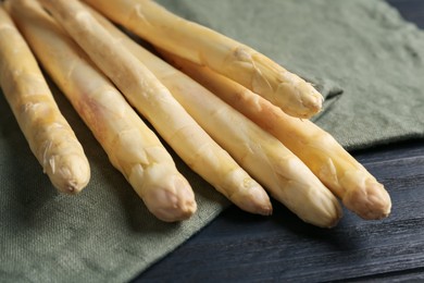 Photo of Raw white asparagus spears on black wooden table, closeup